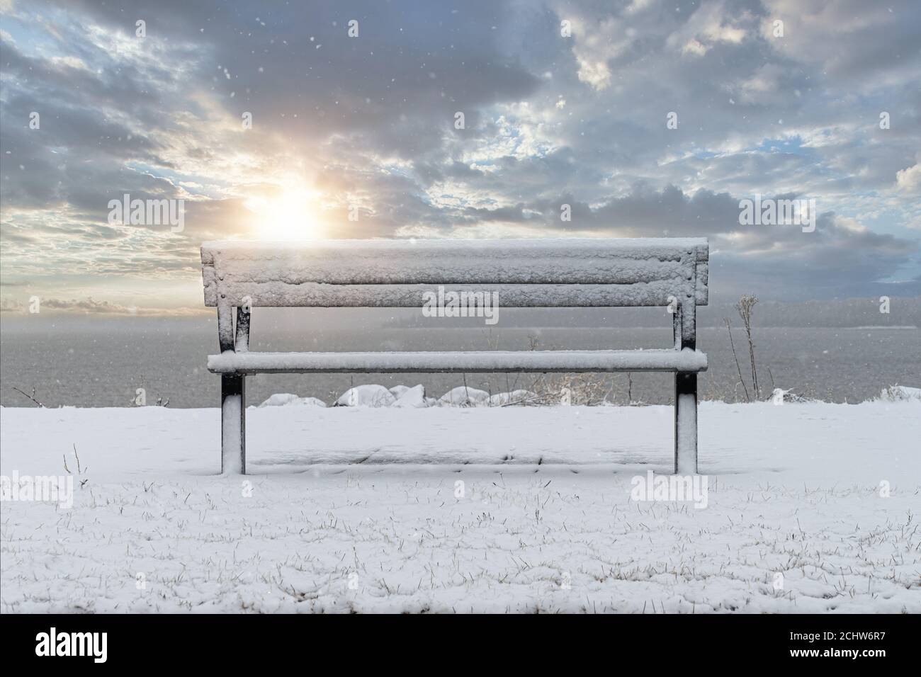 Parkbank mit Schnee bedeckt mit Blick auf den Hafen. Stockfoto