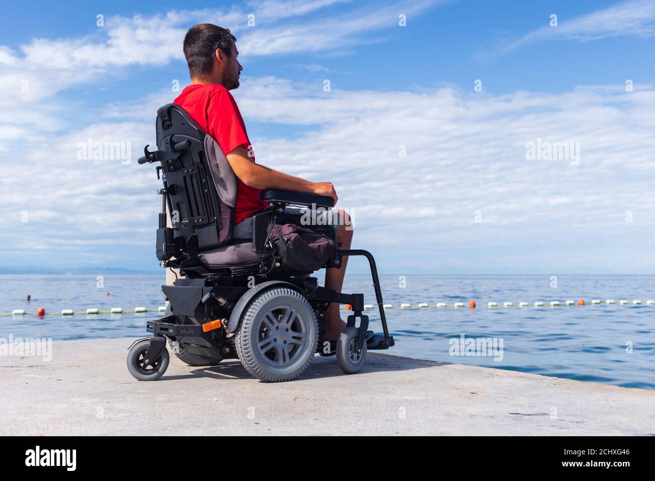 Mann im Rollstuhl mit Blick auf das Meer in den Sommerferien. Stockfoto