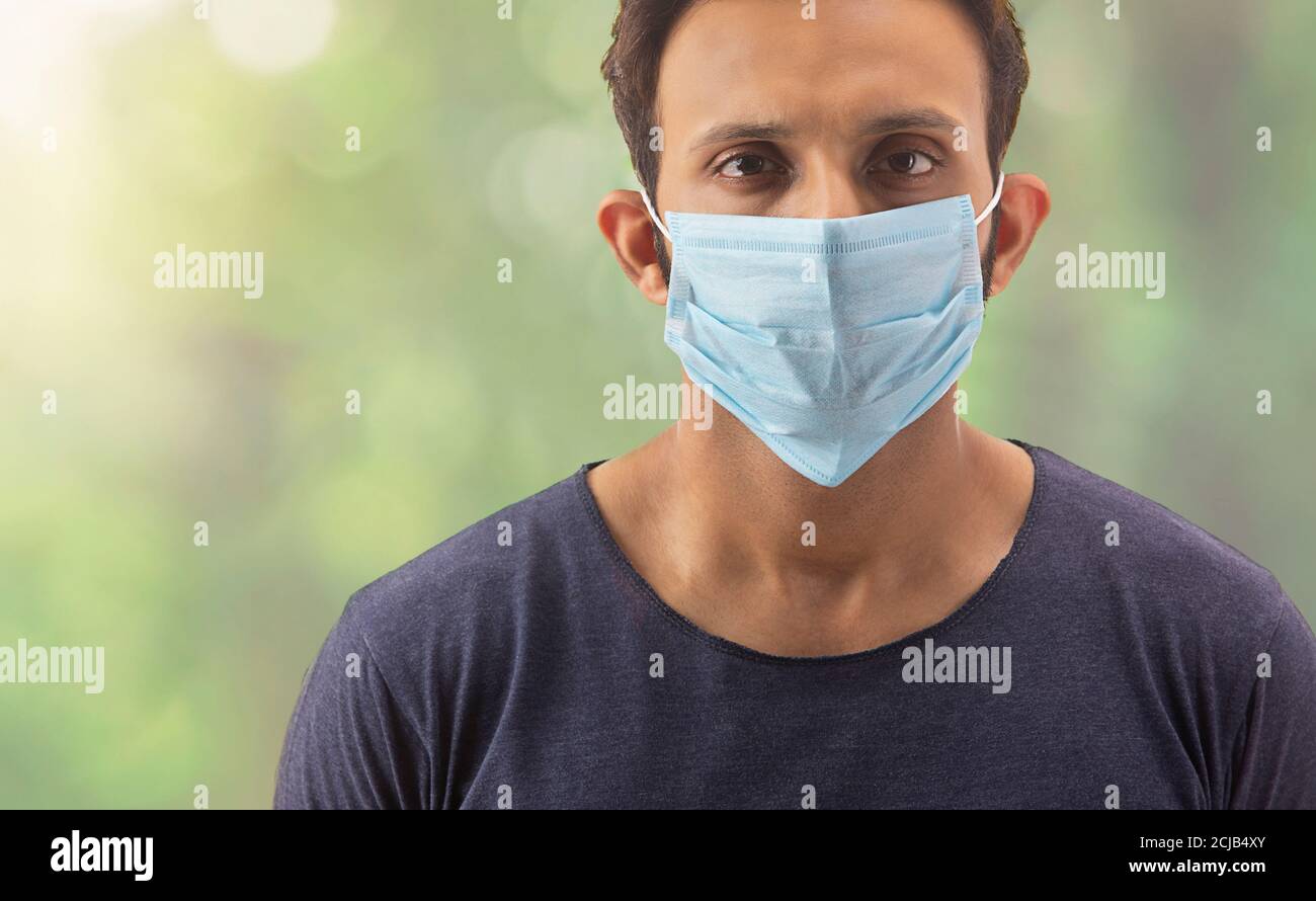 Junger Mann mit seinem Gesicht in einer Maske Schutz bedeckt Sich selbst von Infektionen Stockfoto