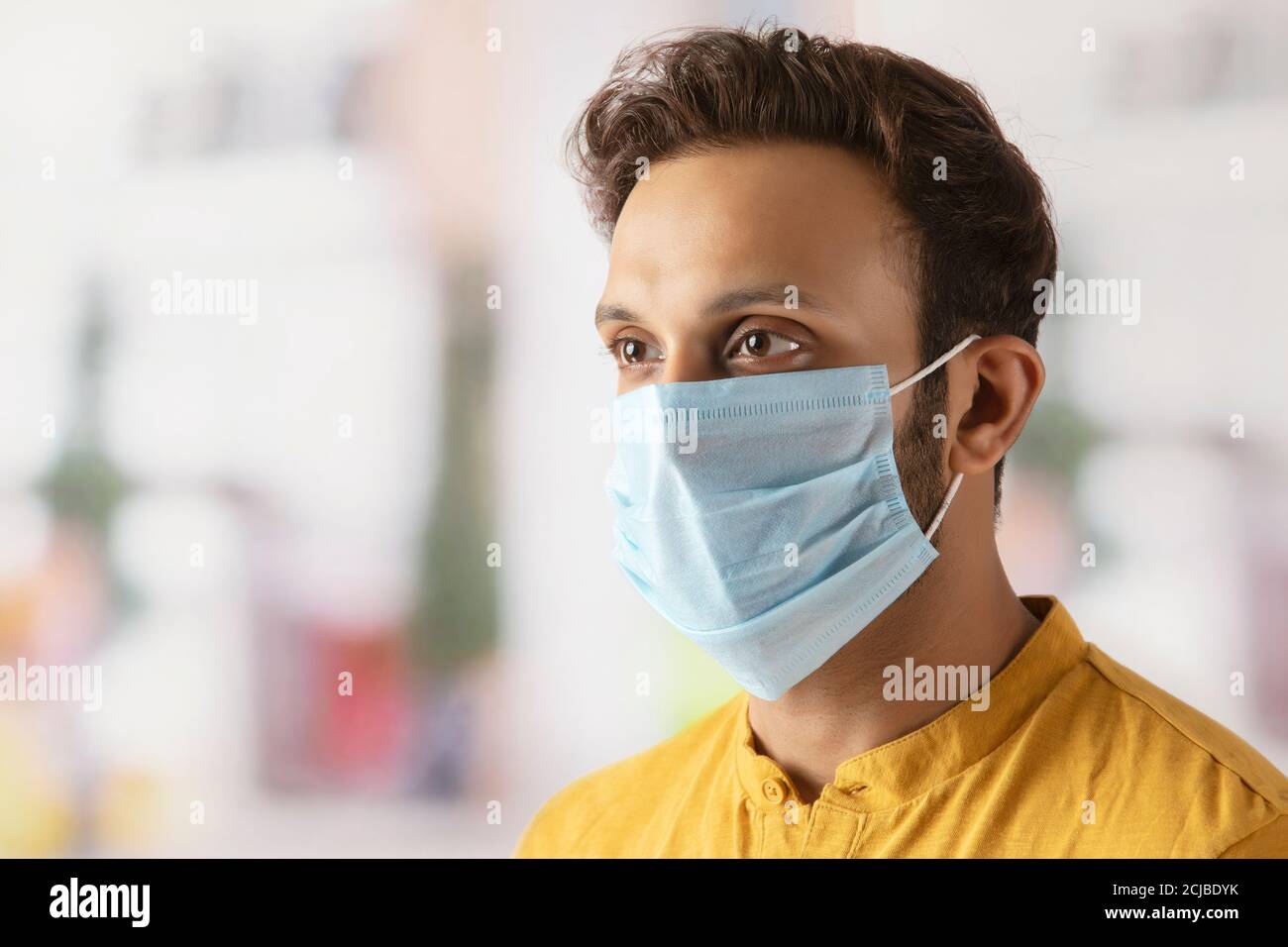 Junger Mann, der sich beim Gehen durch das Tragen einer Maske schützt Im Freien Stockfoto