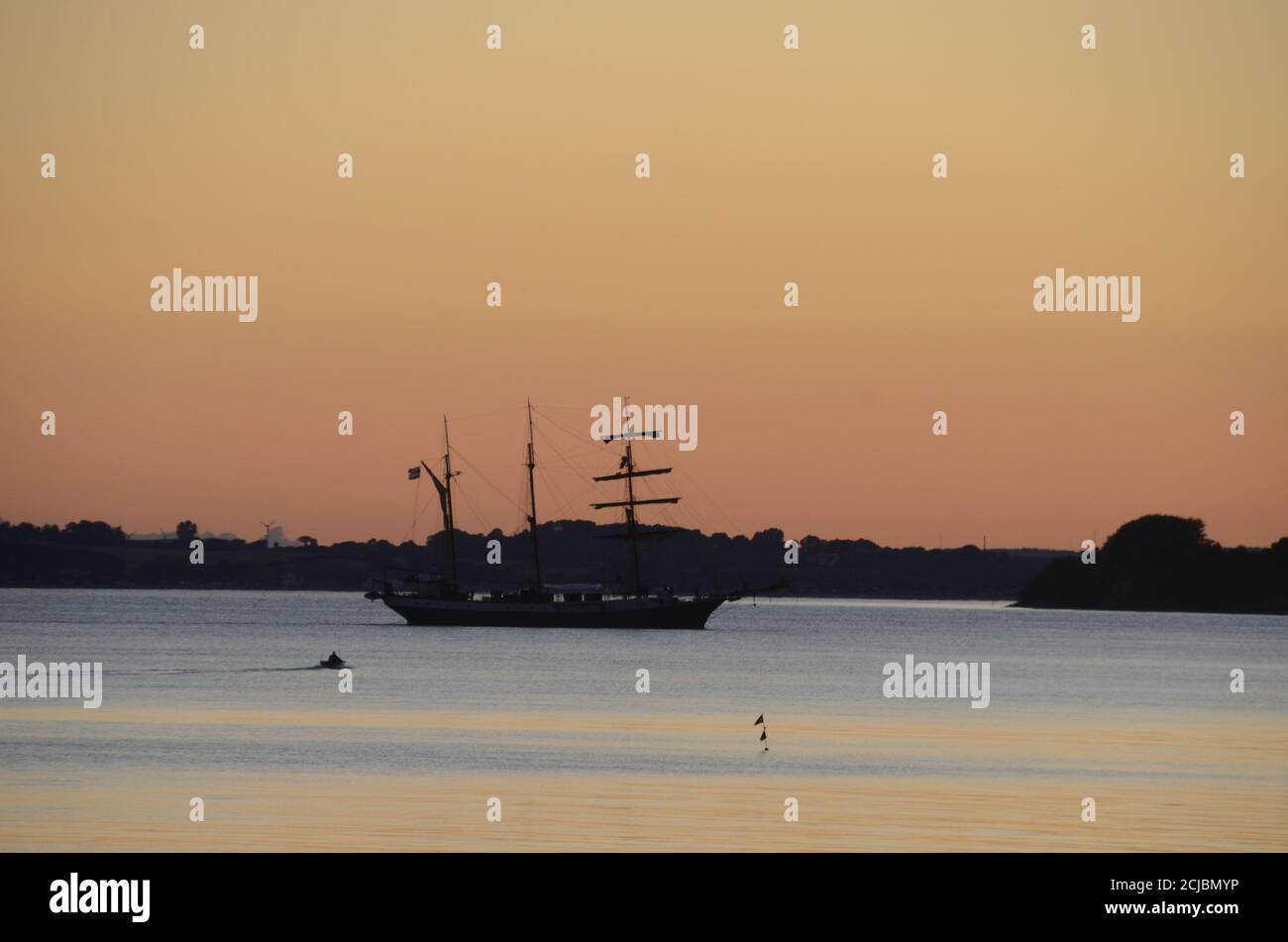 Altes Segelschiff geht im Abendlicht auf einem ruhigen Meer in den Hafen. Stockfoto