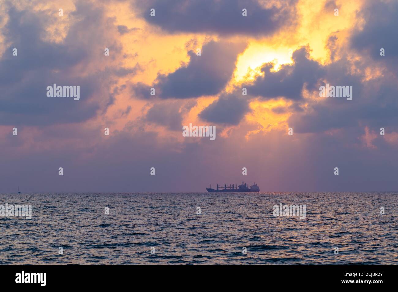 Ein Schiff im Mittelmeer gegen den Sonnenuntergang. Ein Blick vom Strand in Ashdod, Israel. Stockfoto