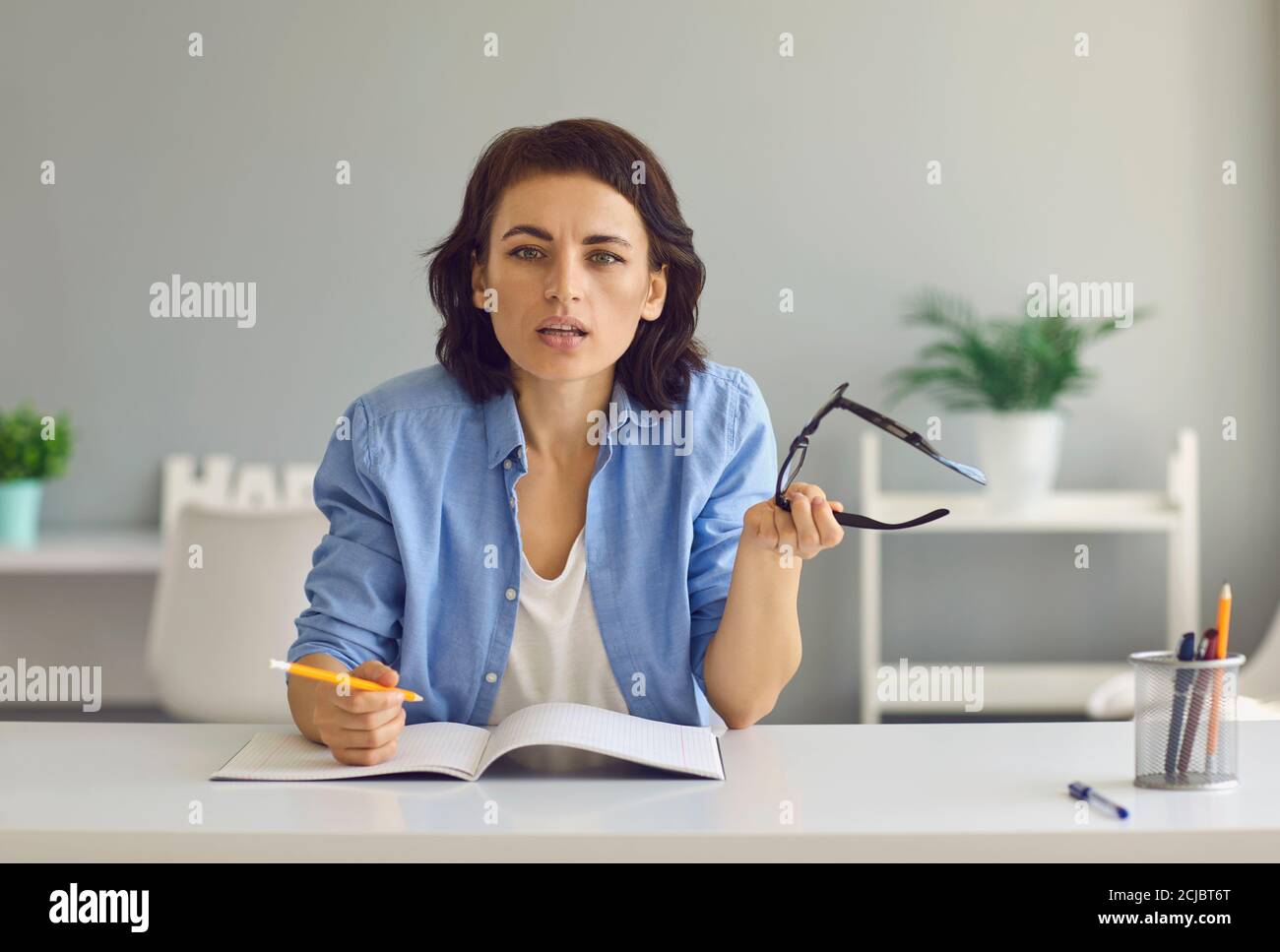 Junge Frau im Gespräch mit jemandem während Online-Treffen von zu Hause Stockfoto