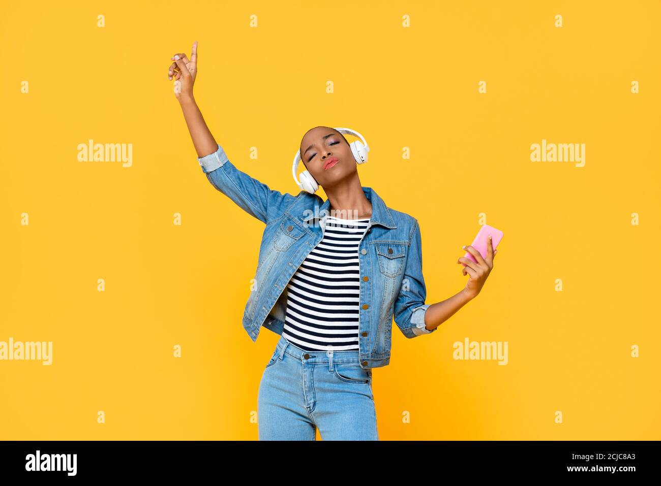 Glückliche junge afroamerikanische Frau trägt Kopfhörer hören und bewegen Zur Musik auf gelbem Hintergrund isoliert Stockfoto