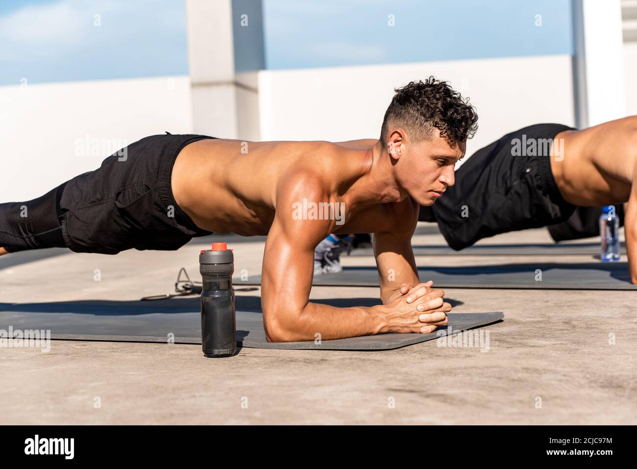 Muskulöser Sportmann, der Plank-Übung im Freien macht Auf dem Dach des Gebäudes Stockfoto