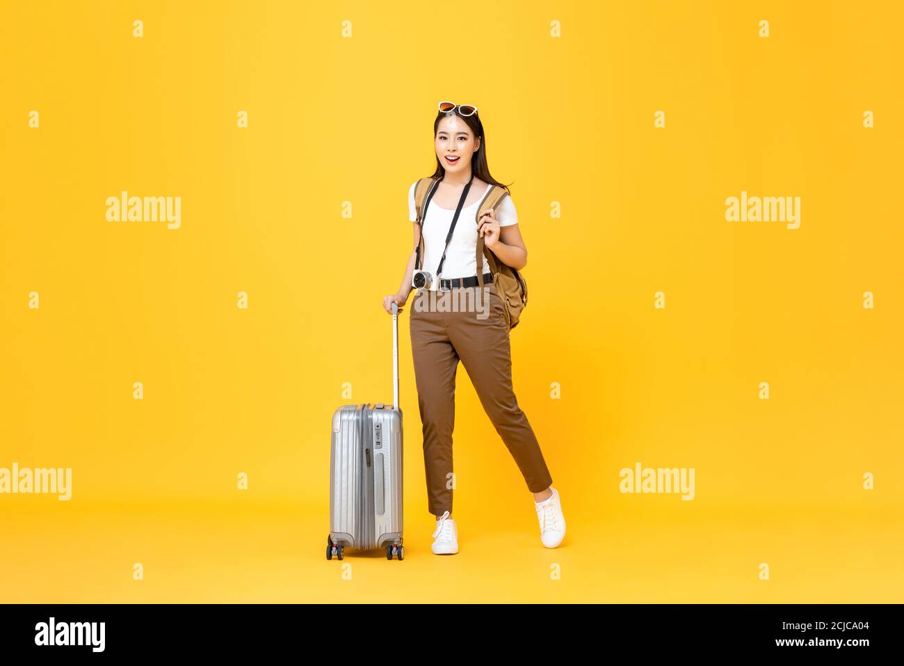 In voller Länge Porträt von lächelnd niedlich junge asiatische Frau Tourist Mit Gepäck isoliert auf gelben Studio Hintergrund Stockfoto
