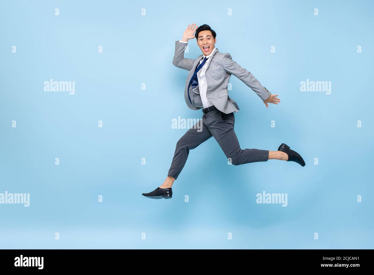 Voller Länge Spaß Porträt von glücklich energisch junge asiatische Geschäftsmann Springen in der Luft isoliert auf Studio blauen Hintergrund mit Kopie Platz Stockfoto