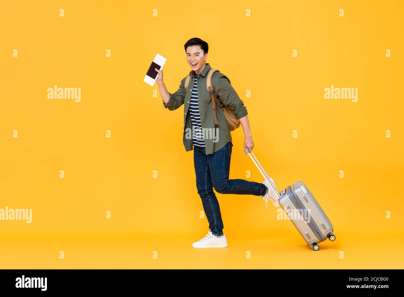 In voller Länge Porträt von lächelnd glücklich gut aussehende junge asiatische Mann Tourist mit Pass und Gepäck bereit, um im Urlaub zu reisen Isoliert in gelber studi Stockfoto In voller Länge Porträt von lächelnd glücklich gut aussehende junge asiatische Mann Tourist mit Pass und Gepäck bereit, um im Urlaub zu reisen Isoliert in gelber studi Stockfoto