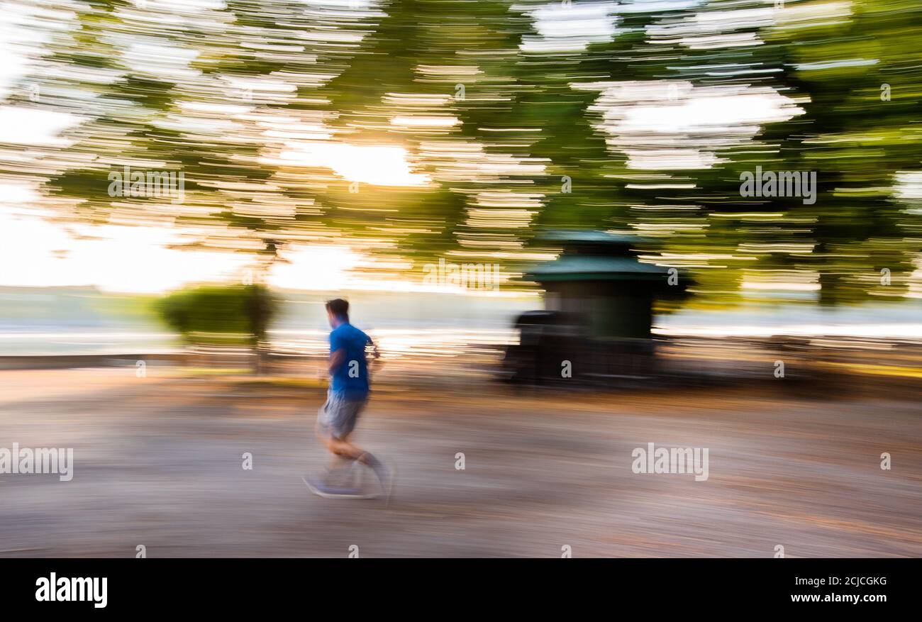 Hannover, Deutschland. September 2020. Ein Mann, der bei Sonnenaufgang am Maschsee entlang joggt (aufgenommen mit langer Verschlusszeit und bewegter Kamera). Kredit: Julian Stratenschulte/dpa/Alamy Live Nachrichten Stockfoto