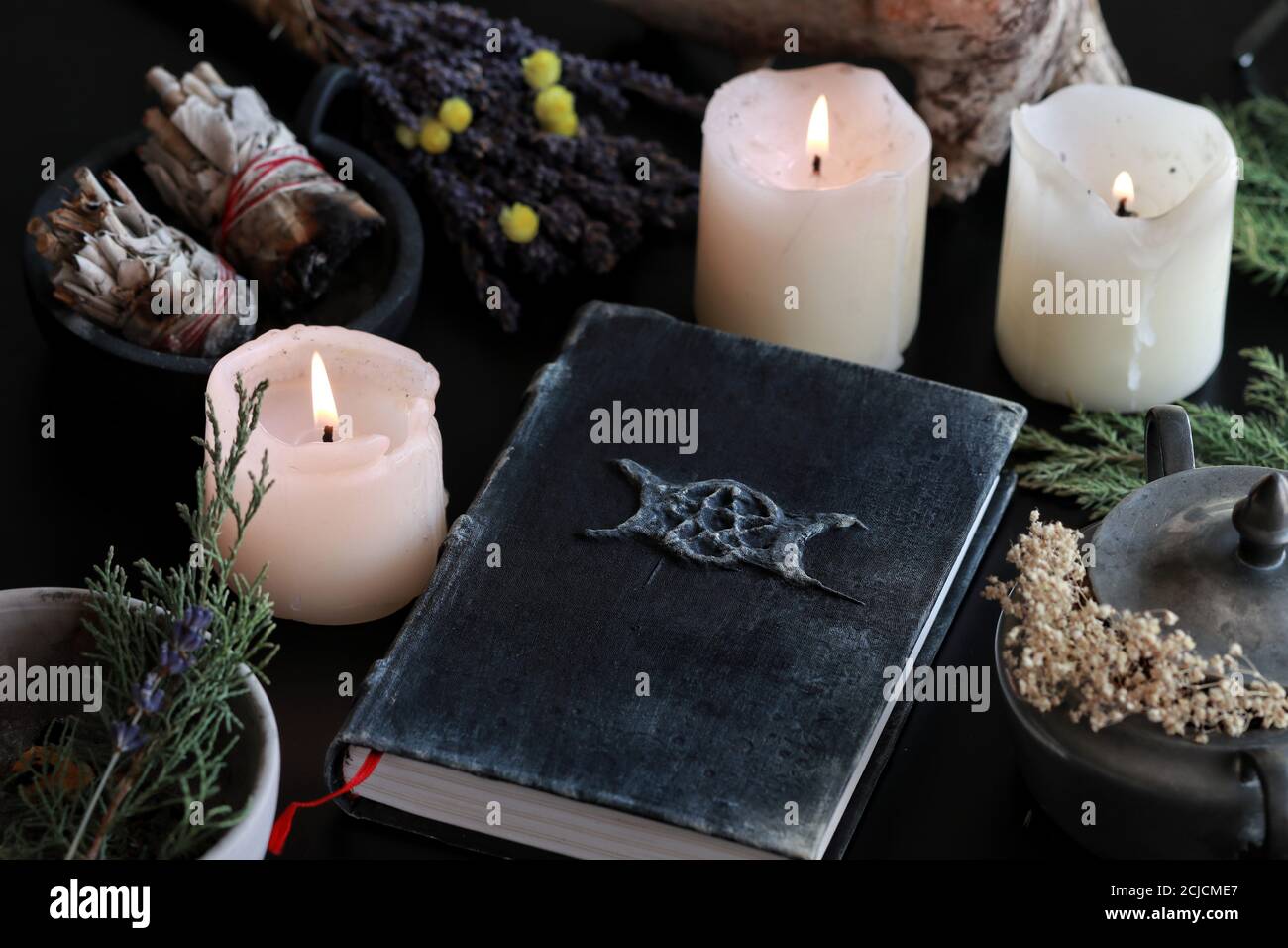 Wiccan Hexenaltar mit einem Hand gemacht alt aussehende Buch Grimoire mit dreifachen Mond Symbol, und andere verschiedene Gegenstände - getrocknete Blumen, Naturelemente Stockfoto
