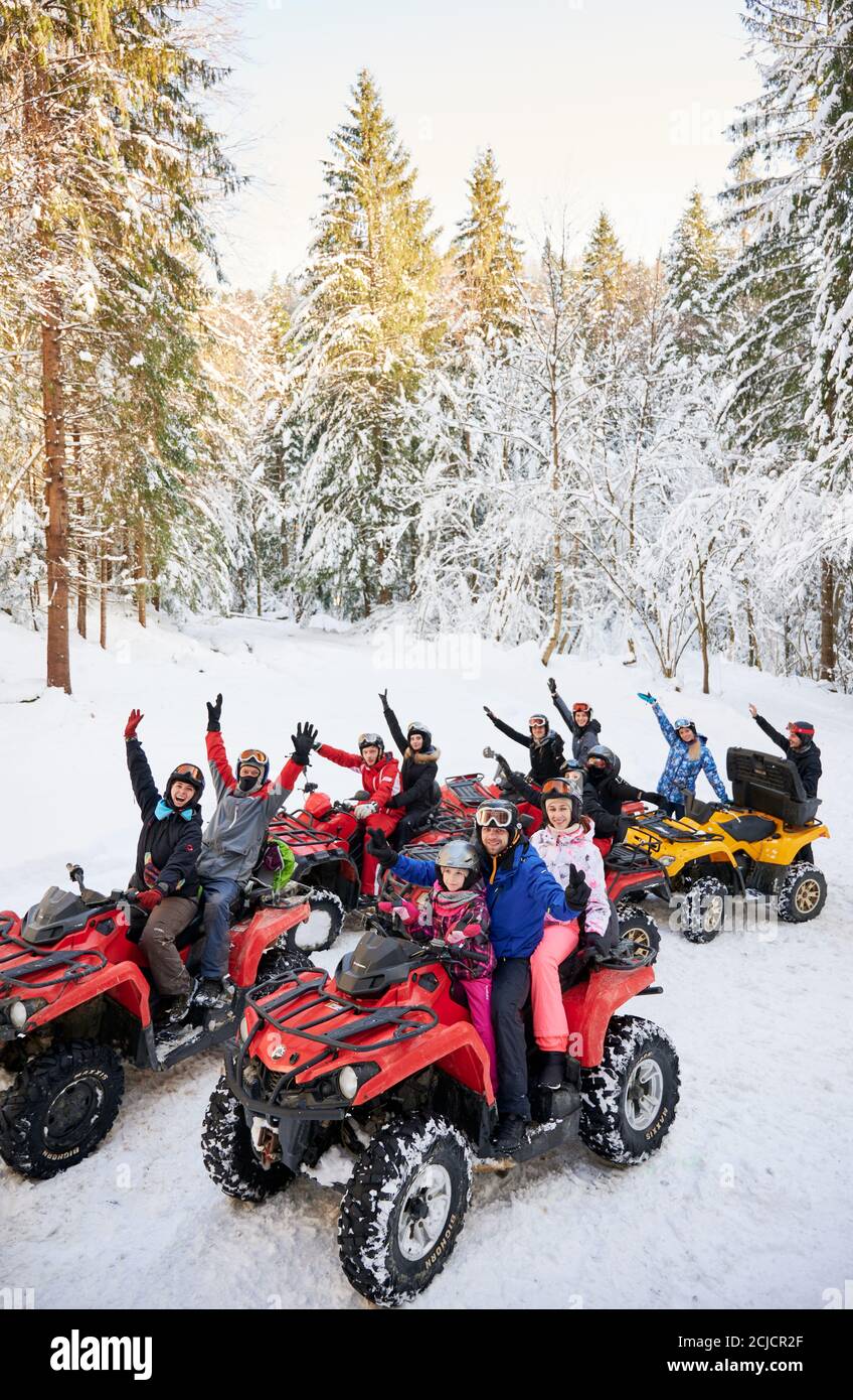 Yaremche, Ukraine - 02. Februar 2020: Gruppe von fröhlichen Menschen sitzen auf vier Rädern ATV Fahrräder, genießen schönen Wintertag in verschneiten Bergen, erstaunliche schneebedeckten hohen Fichten auf dem Hintergrund. Stockfoto