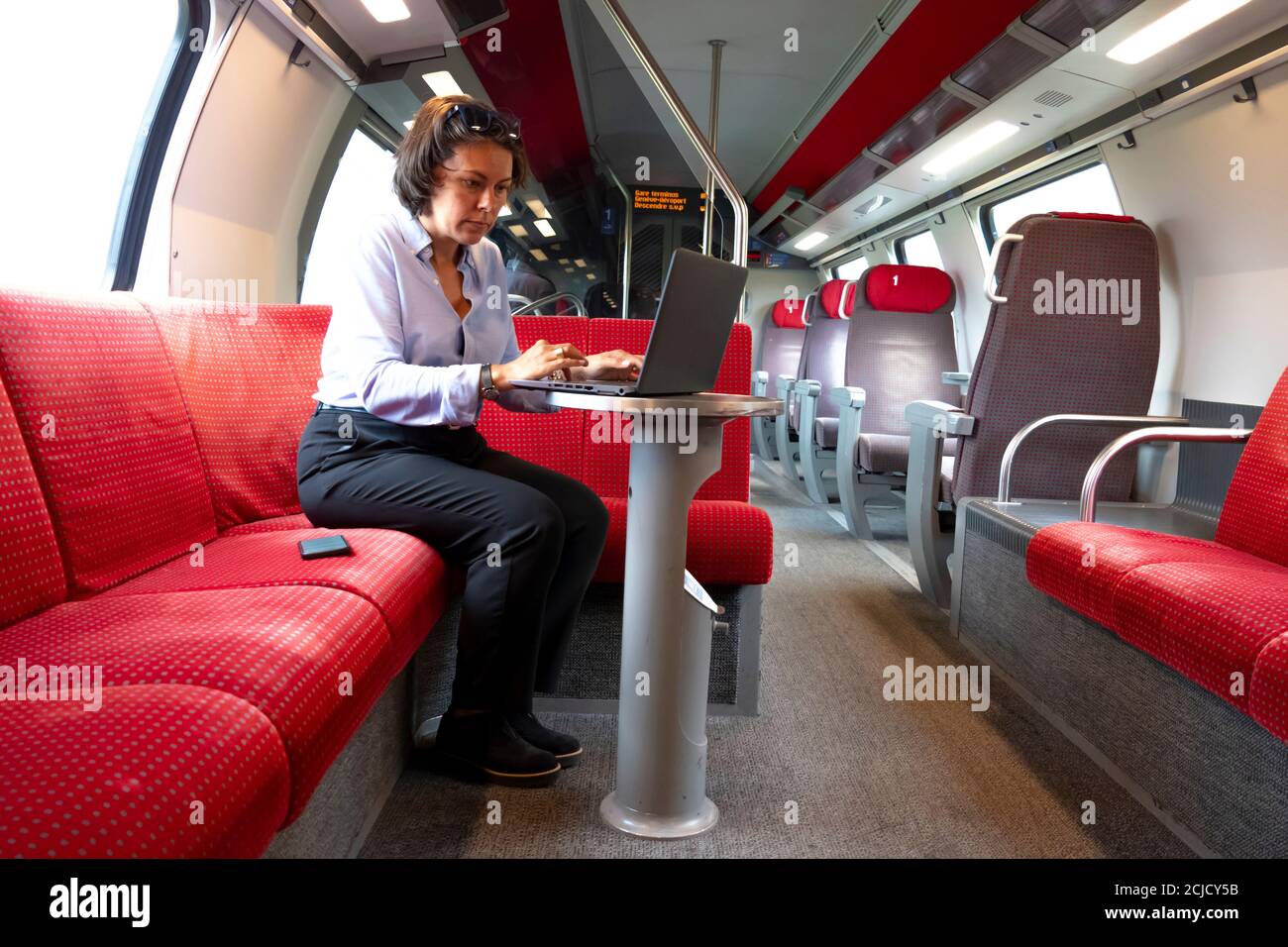 Business Woman in der ersten Klasse der Bahn sitzend, Arbeiten mit Laptop  und Mobiltelefon, Schweiz Stockfotografie - Alamy