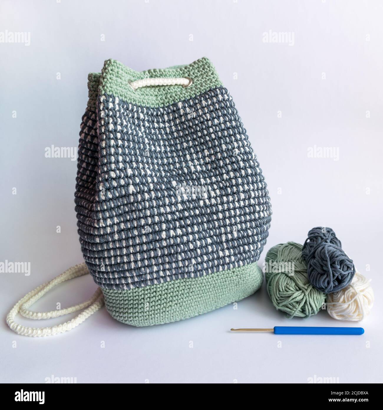 Handgefertigter gehäkelter Mosaikeimer Rucksack in Pastellgrün, Weiß und Grau Farben Stockfoto