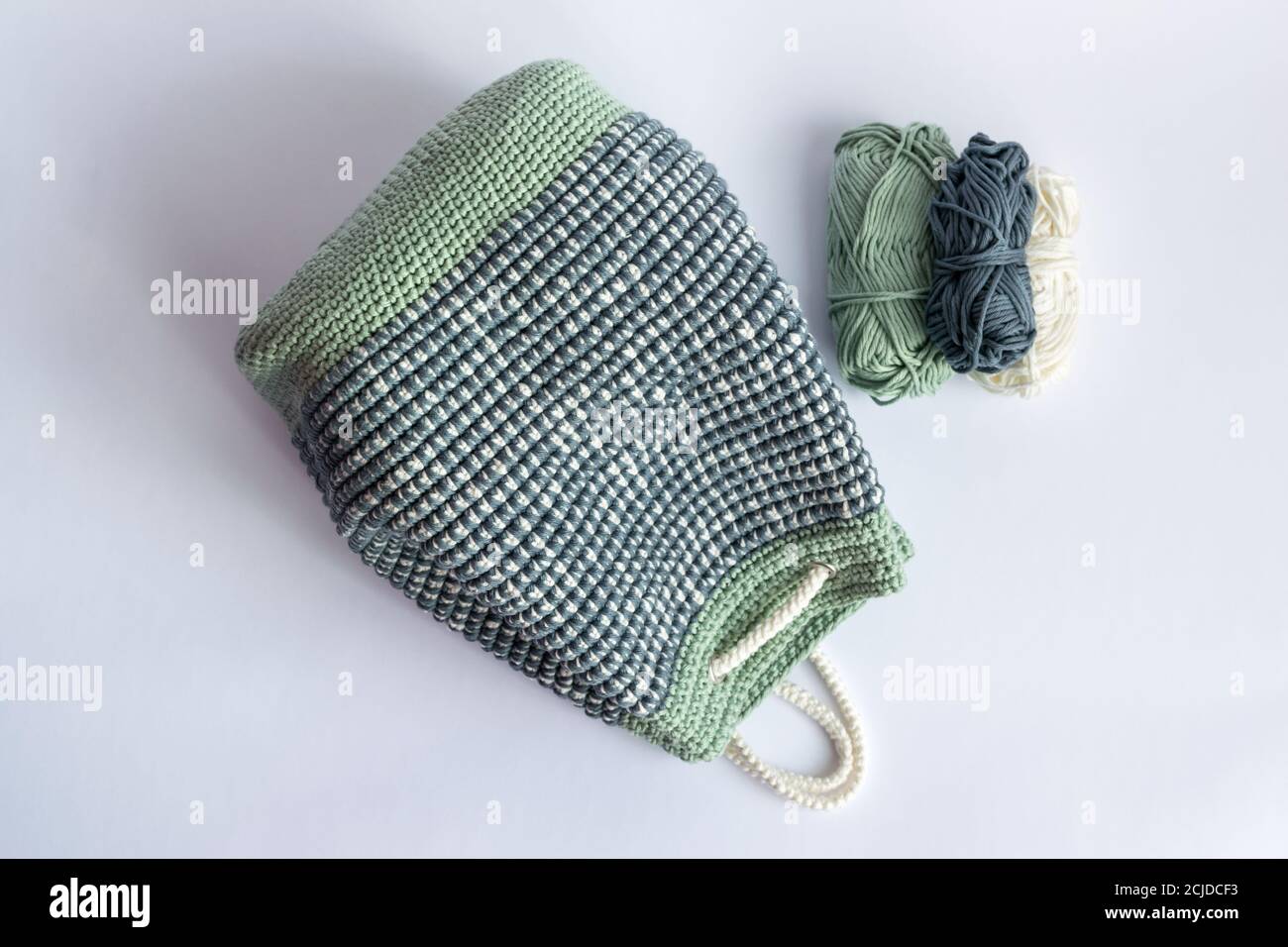 Handgefertigter gehäkelter Mosaikeimer Rucksack in Pastellgrün, Weiß und Grau Farben Stockfoto