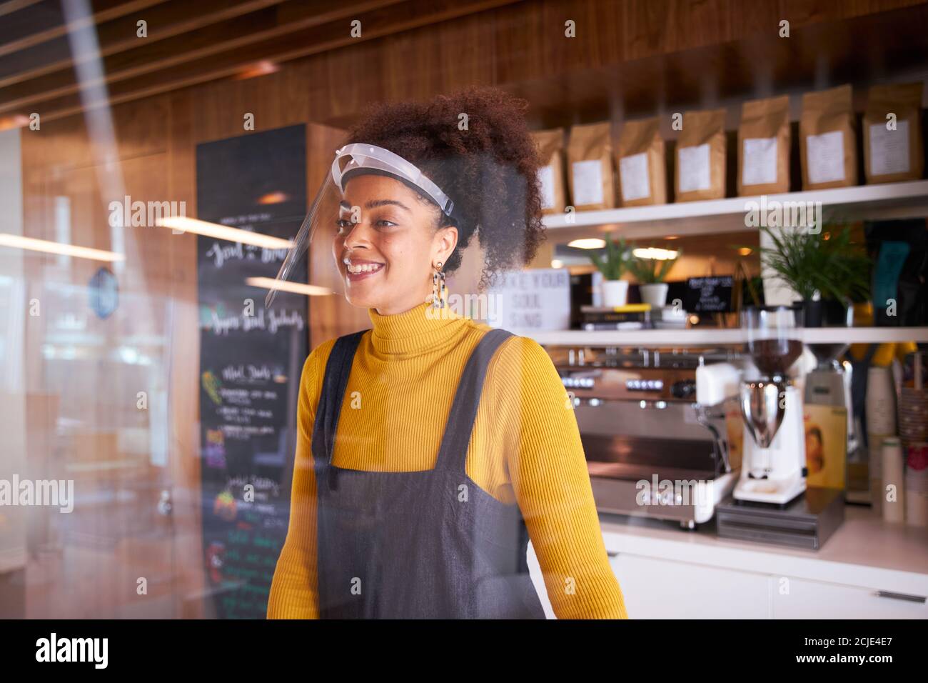 Weibliche Kleinunternehmerin Des Coffee Shops Mit Gesichtsschild Hinter Dem Zähler Während Der Gesundheitsinpandemie Stockfoto