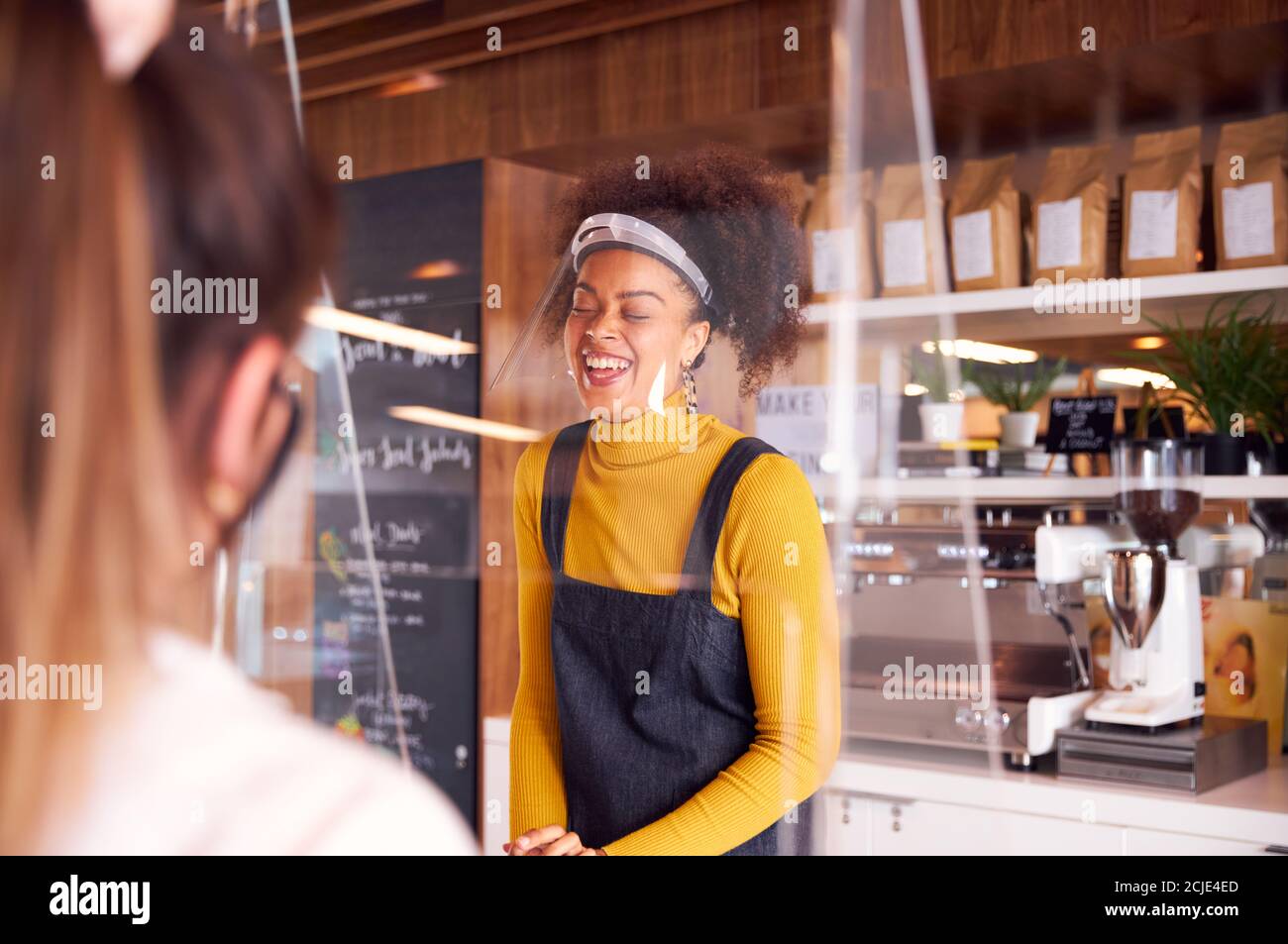 Lachende Frau, Die Im Coffee Shop Mit Gesichtsschild Arbeitet Kunde Während Einer Gesundheitsinpandemie Stockfoto