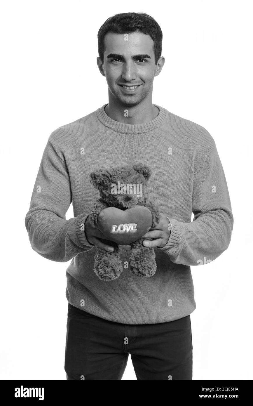 Junger glücklicher iranischer Mann hält Teddybär mit Herz und Liebe Zeichen bereit für Valentinstag Stockfoto