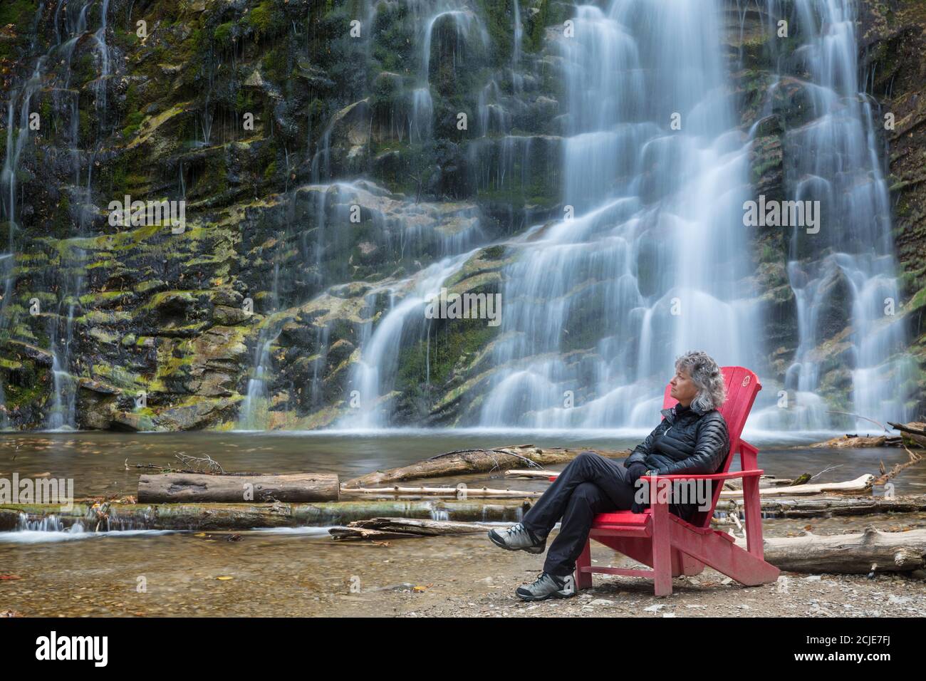 Frau im roten Stuhl in La Chute, Forillon National Park, Gaspésie, Quebec, Kanada Stockfoto