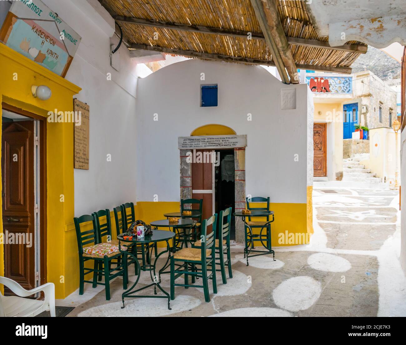 Olympos, Karpathos, Griechenland - 16. September 2019: Kleiner, schmaler Platz in Olympos mit griechischem Kaffeeplatz - Kafenion und kleiner Kapelle daneben Stockfoto