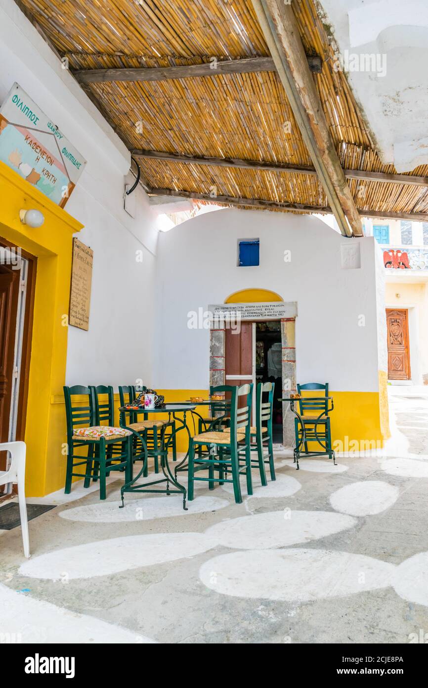 Olympos, Karpathos, Griechenland - 16. September 2019: Kleiner, schmaler Platz in Olympos mit griechischem Kaffeeplatz - Kafenion und kleiner Kapelle daneben Stockfoto