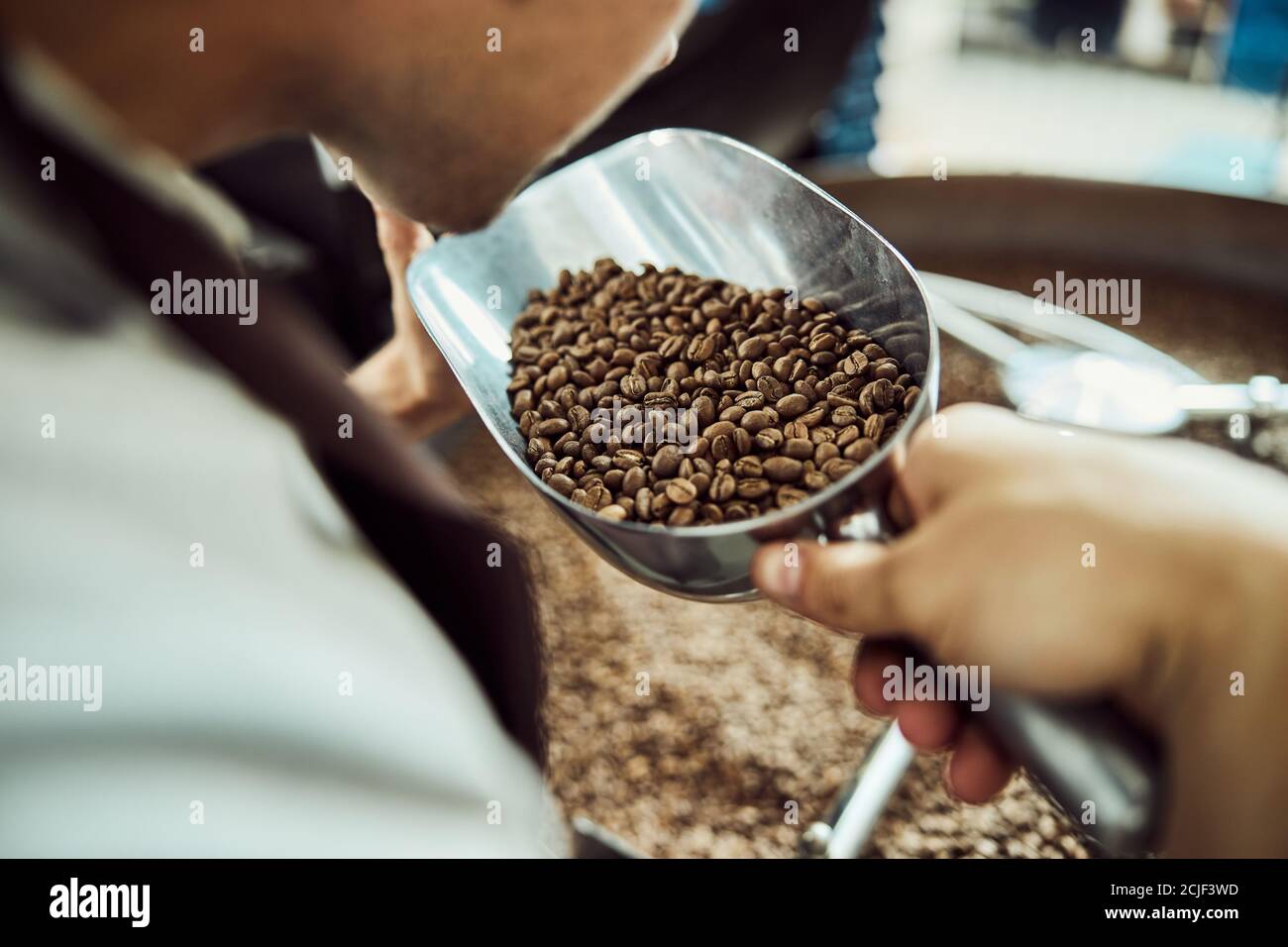 Junger Mann riecht frisch geröstete Kaffeebohnen Stockfoto