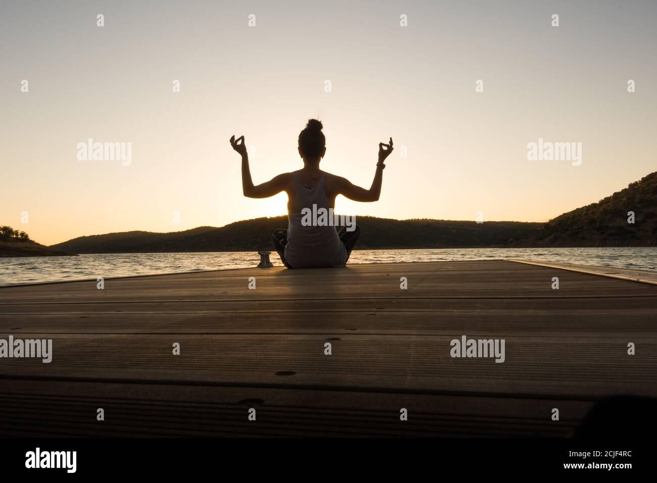 Junges Mädchen tut Yoga Posen auf einem Pier bei Sonnenuntergang. Perfekte Körperhaltung Stockfoto