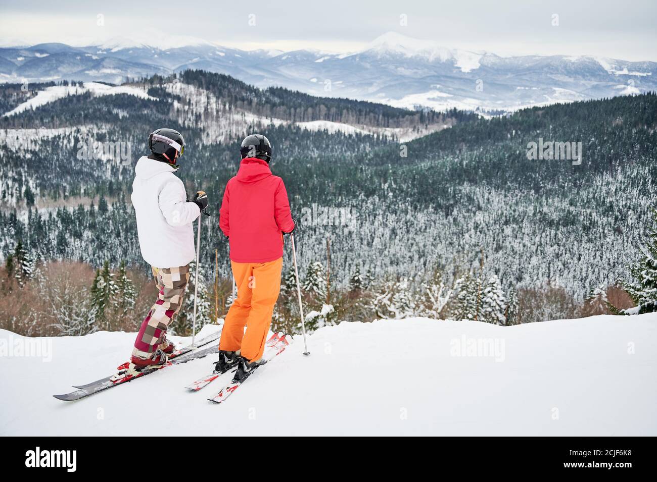Zwei Freunde in Skianzügen und Skiausrüstung sind in den Winterbergen und genießen schneebedecktes Wetter, Skifahren und unglaubliche Landschaften. Rückansicht, Kopierbereich. Wintersportkonzept Stockfoto
