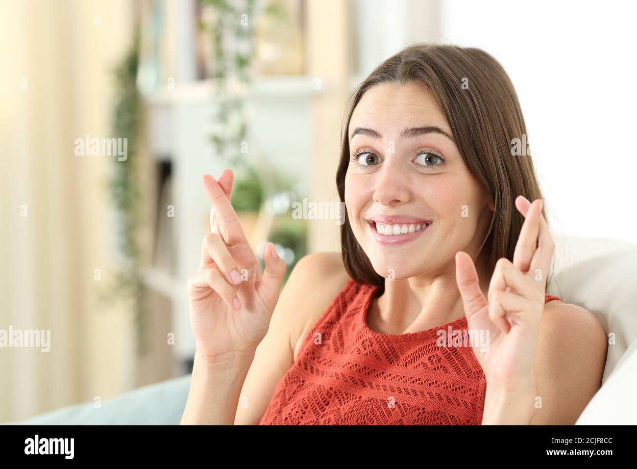 Glücklich teen Crossing Finger sittig auf ein Couch im Wohnzimmer zu Hause Stockfoto