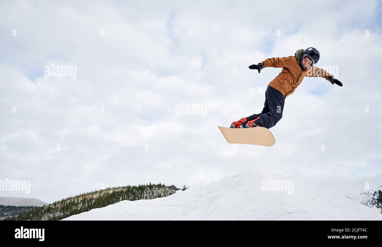 Konzept der extremen Arten von Sport. Snowboarder in farbenfroher Kleidung, die mit dem Snowboard gegen den bewölkten Himmel hoch fliegt. Low-Angle-Ansicht, Kopierbereich. Liebe zum Sport Stockfoto