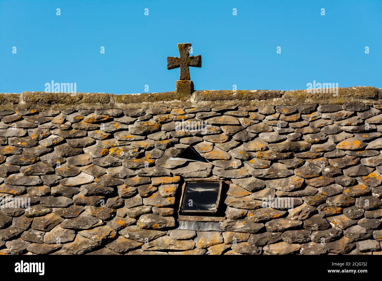 Steinkreuz auf dem Lauze Dach eines Hauses als Zeichen des Schutzes, Cantal Department, Auvergne Rhone Alpes, Frankreich Stockfoto