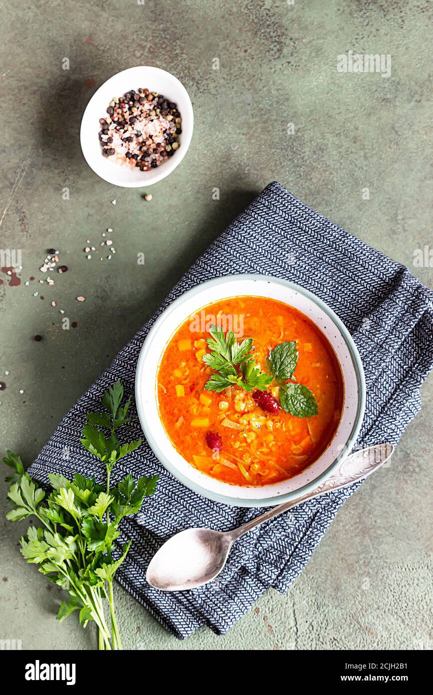 Scharf und würzig, dicke Linsen- und rote Bohnensuppe mit Tomaten aus der Dose und Koriander. Konkreter Hintergrund, selektiver Fokus. Stockfoto