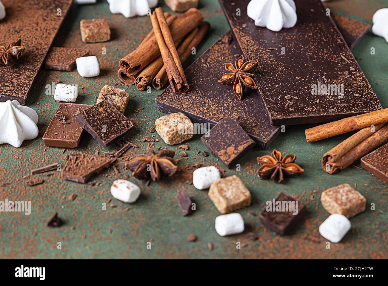 Zutaten für die Herstellung von heißer Schokolade. Dunkle und milchige Schokolade, Kakaopulver, Zimt, Anisstern, brauner Zucker, Marshmallow, Baiser und Milch. Stockfoto