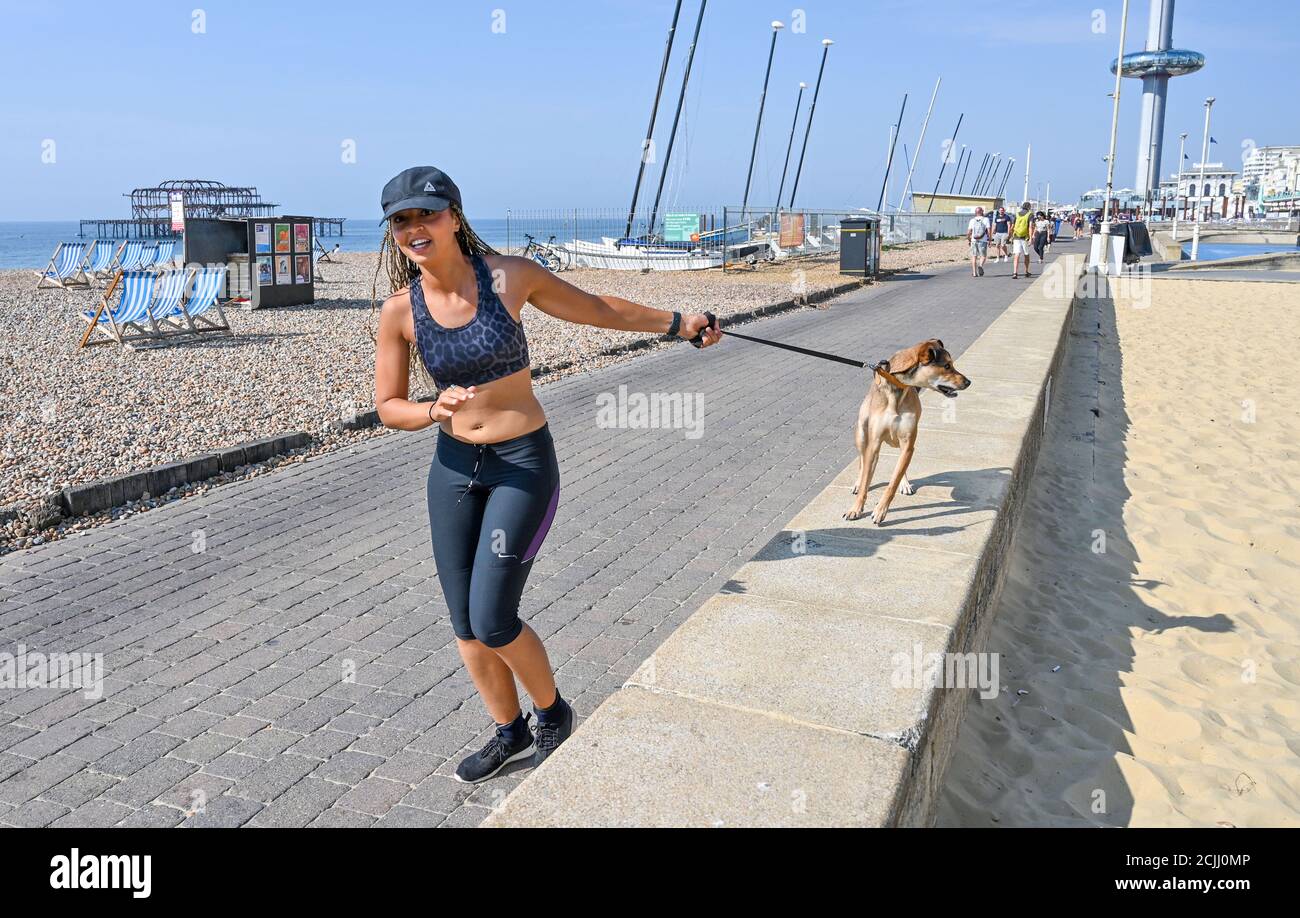 Brighton UK 15. September 2020 - Diese junge Dame nimmt ihren Hund für einen Lauf an der Küste von Brighton, wie sie das Beste aus einem anderen heißen Tag am Meer machen, da die Temperaturen wieder erwartet werden, um 30 Grad in einigen Teilen des Südostens zu erreichen : Kredit Simon Dack / Alamy Live Nachrichten Stockfoto