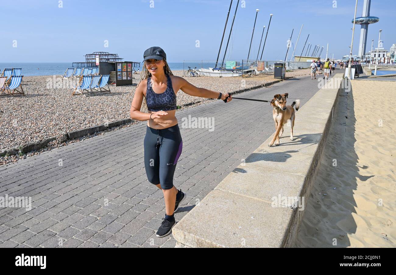 Brighton UK 15. September 2020 - Diese junge Dame nimmt ihren Hund für einen Lauf an der Küste von Brighton, wie sie das Beste aus einem anderen heißen Tag am Meer machen, da die Temperaturen wieder erwartet werden, um 30 Grad in einigen Teilen des Südostens zu erreichen : Kredit Simon Dack / Alamy Live Nachrichten Stockfoto