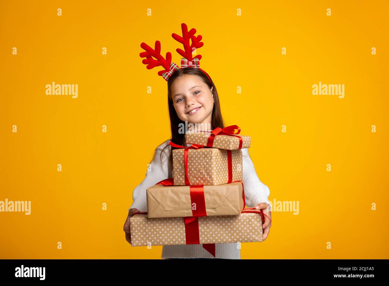 Frohe Weihnachten. Fröhliches Kind mit Hörnern, die viele Geschenke halten Stockfoto