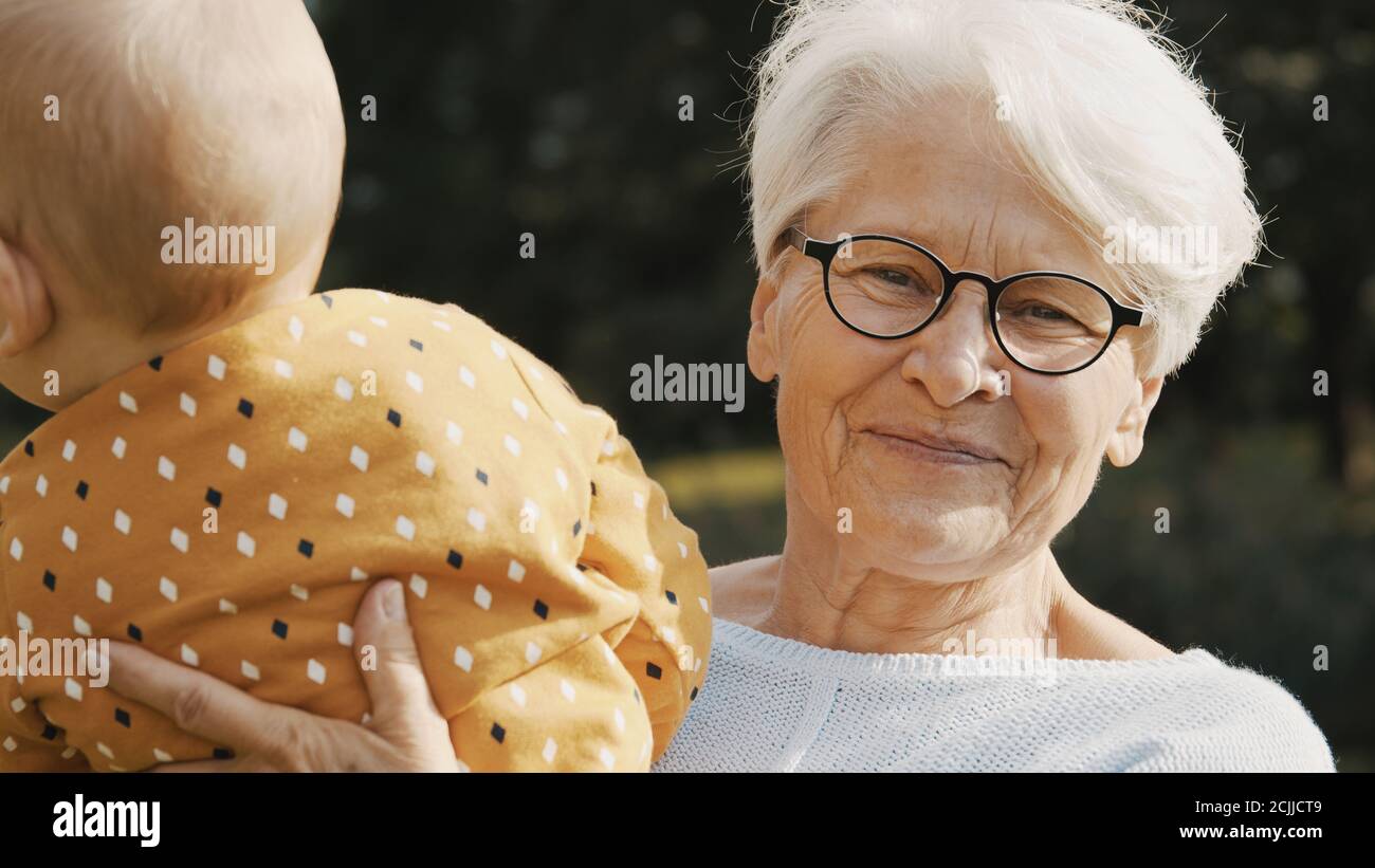 Glückliche Großmutter hält ihr Enkelkind in der Natur. Hochwertige Fotos Stockfoto