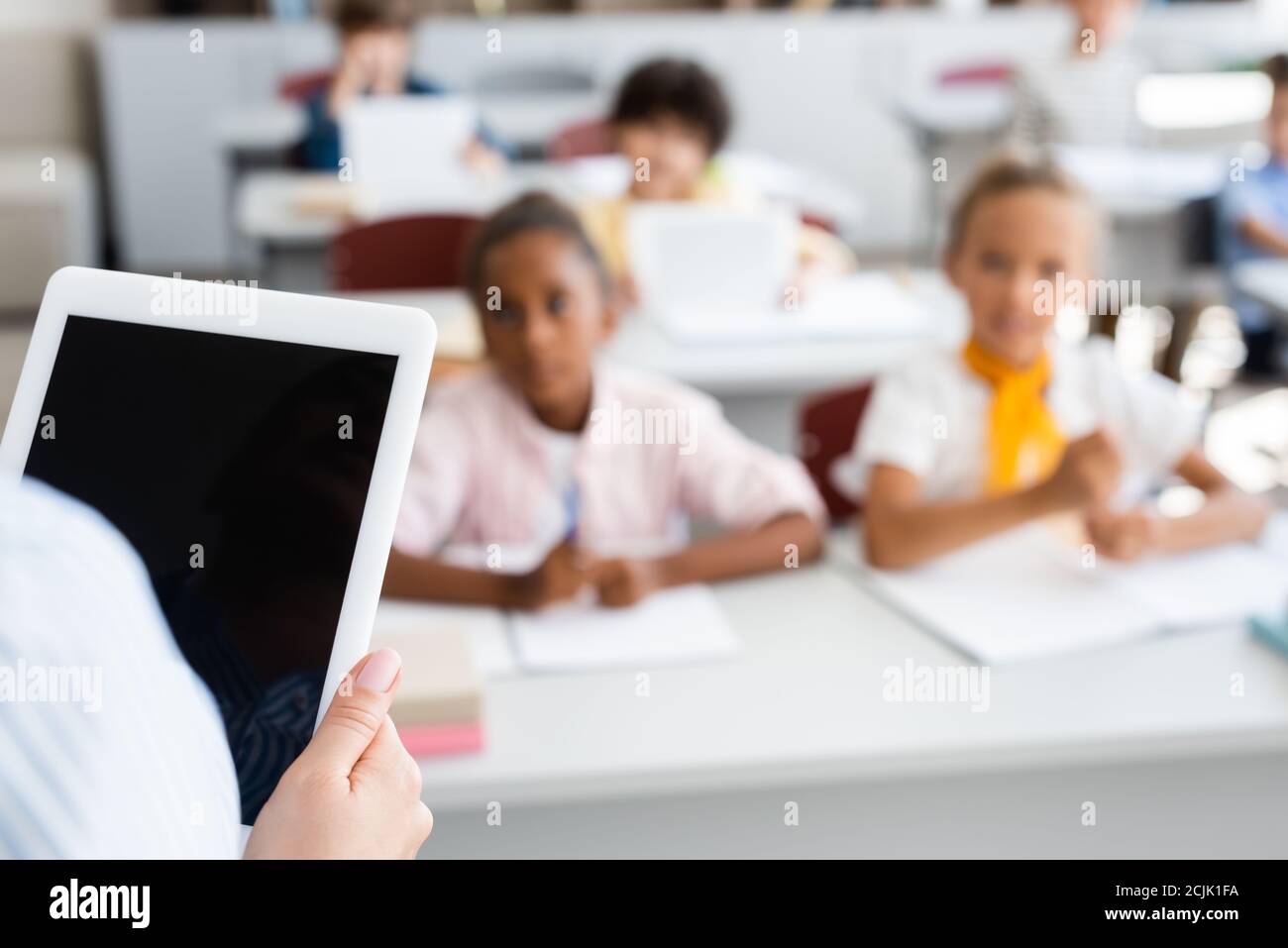 Beschnittene Ansicht des Lehrers mit digitalem Tablet mit leerem Bildschirm In der Nähe von multiethnischen Schülern Stockfoto