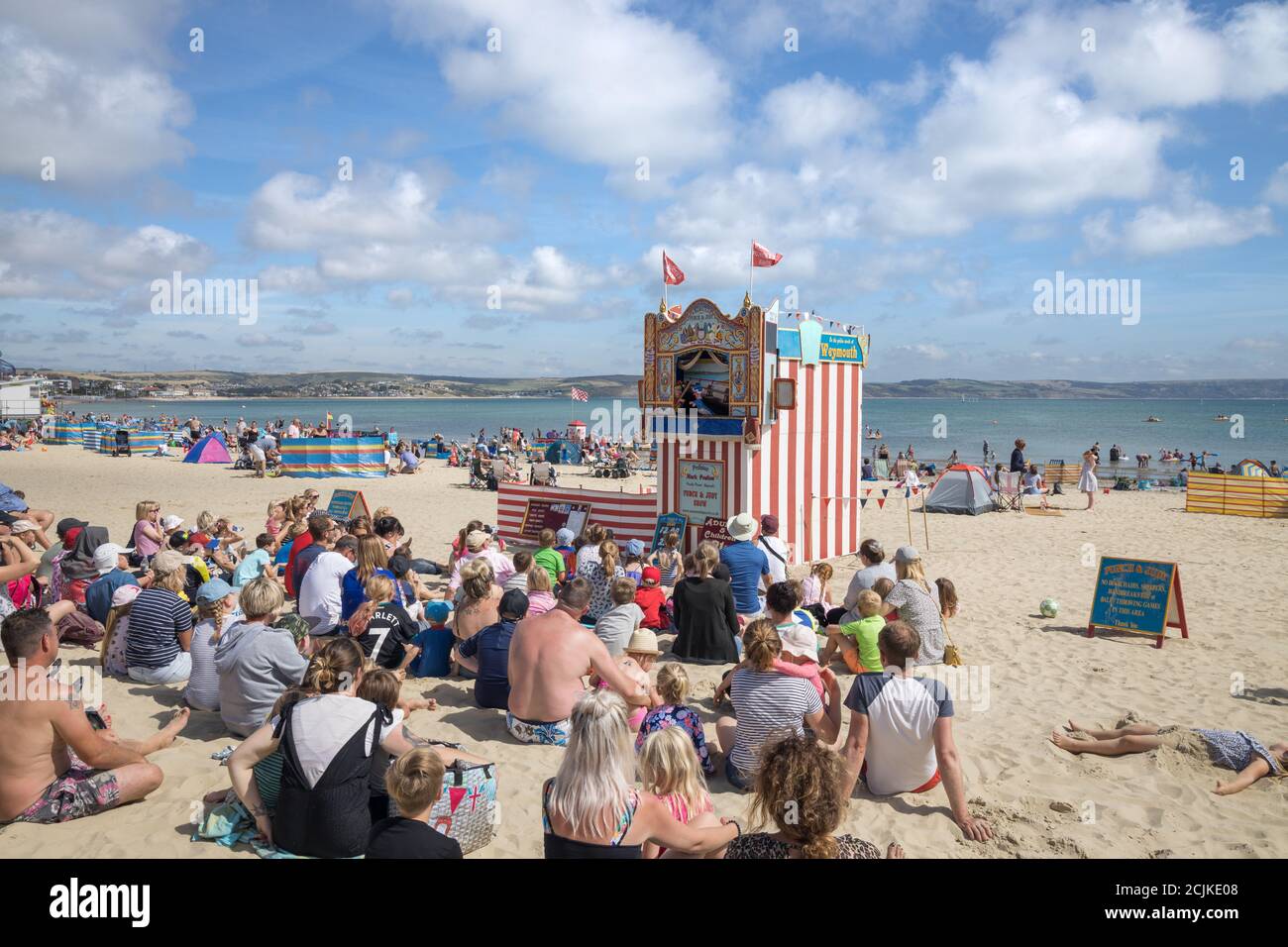Urlauber am Strand mit Punch & Judy, Weymouth, Jurassic Coast, Dorset, England, Großbritannien Stockfoto