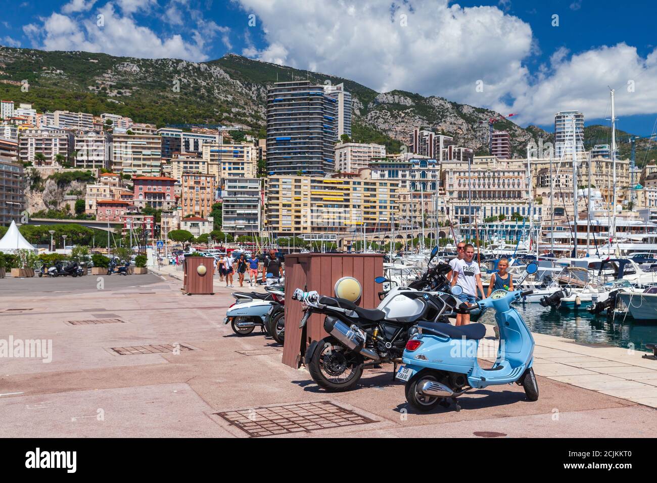 Monte Carlo, Monaco - 15. August 2018: Geparkte Roller stehen in Port Hercule, Touristen gehen die Straße von Monaco Stadt Stockfoto