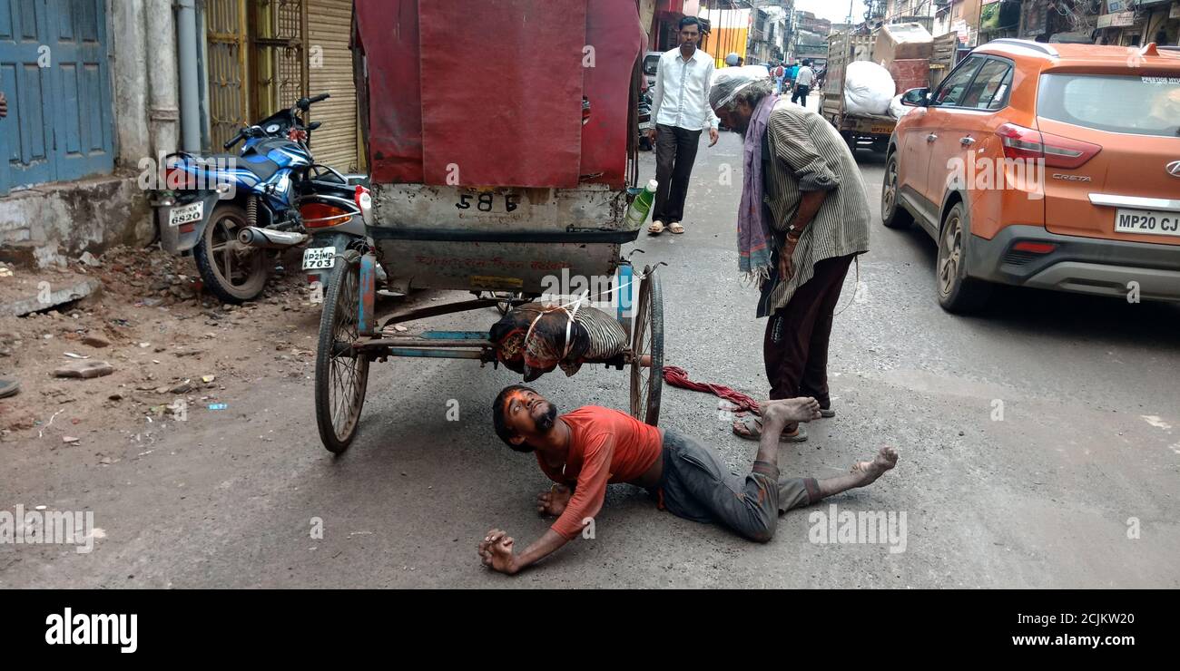 DISTRIKT KATNI, INDIEN - 19. SEPTEMBER 2019: Ein indischer armer behinderter Mann, der auf der Straße für den Transport liegt. Stockfoto