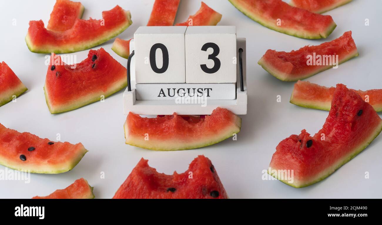 Holzkalender und Wassermelonenschale. 03. August, National Watermelon Day. Viel Wassermelone gegessen. Stockfoto