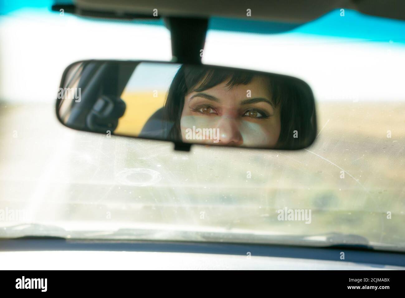 Weibliche Augen in der Spiegelung des Autospiegels. Stockfoto