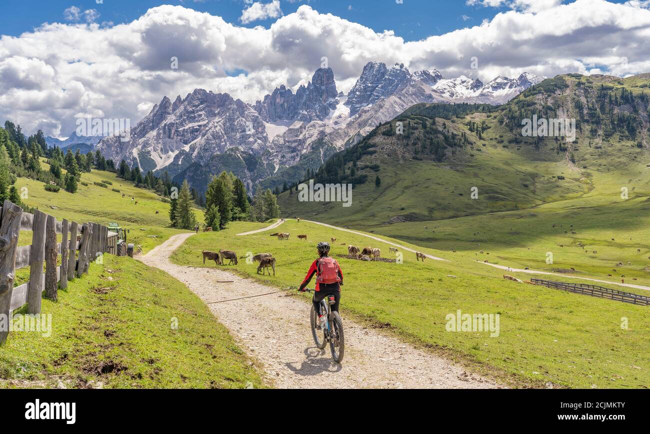 Nette und aktive ältere Frau auf ihrem elektrischen Mountainbike auf dem Hochplateau von Prato Piazzo in den drei Gipfeln Dolomiten, felsige Silhouette Stockfoto