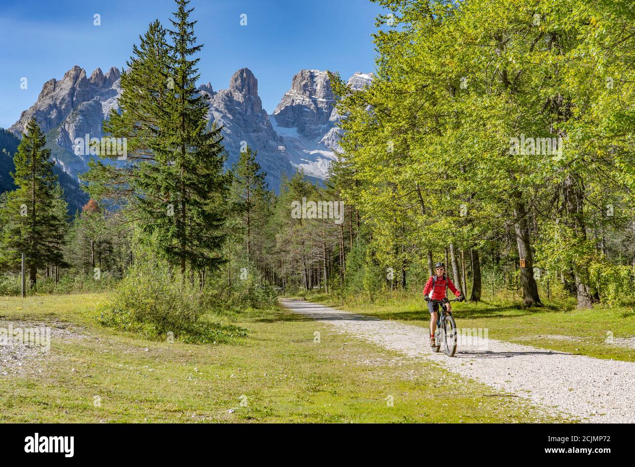 Nette und aktive ältere Frau, die ihr elektrisches Mountainbike reitet Auf einem alten Bahndamm im Höhlensteiner Tal dazwischen Toblach und Cortina Talsperre Stockfoto