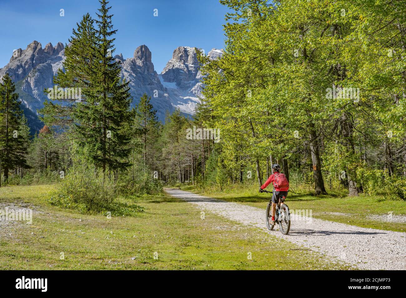Nette und aktive ältere Frau, die ihr elektrisches Mountainbike reitet Auf einem alten Bahndamm im Höhlensteiner Tal dazwischen Toblach und Cortina Talsperre Stockfoto