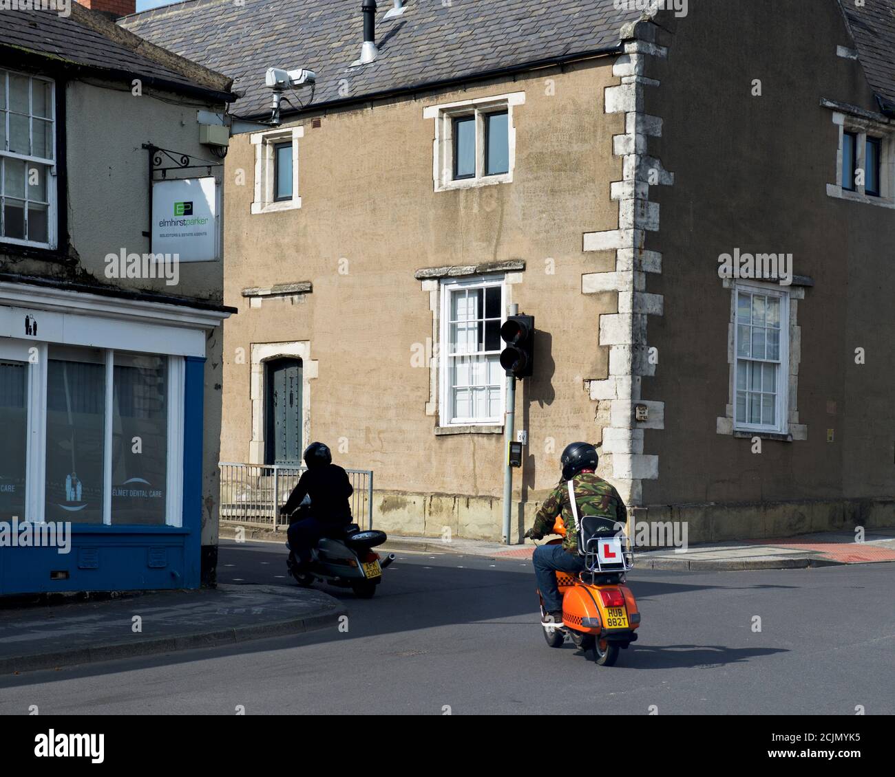 Junge Männer reiten Roller durch Kreuzung, England Großbritannien Stockfoto
