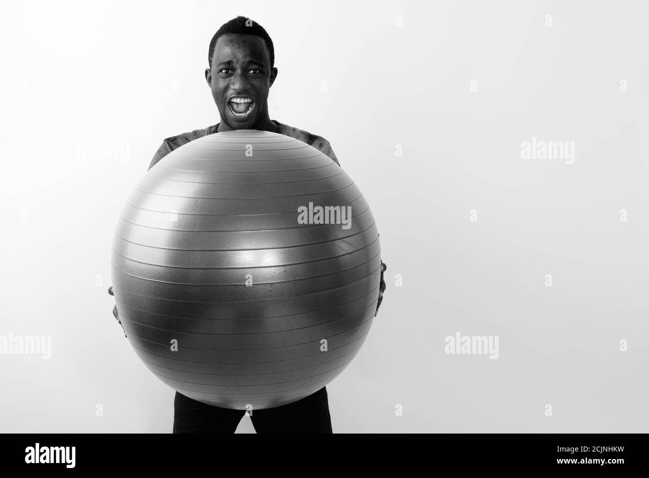 Studioaufnahme eines jungen schwarzen afrikanischen Mannes, der große Übung hält Ball bereit für das Fitnessstudio vor weißem Hintergrund Stockfoto