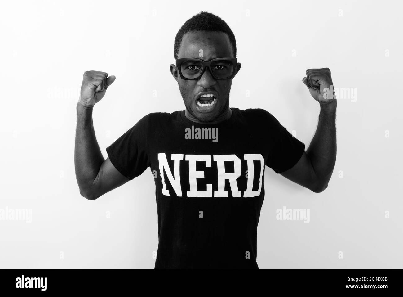 Studio-Aufnahme von jungen schwarzen afrikanischen Geek Mann trägt Nerd shirt, während er seine Arme beugt und Bizeps zeigt Stockfoto