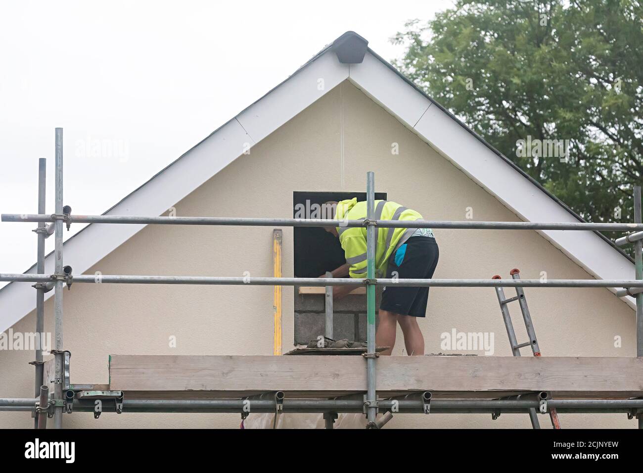 Mann blockiert ein Haus Giebel Ende Fenster, die nicht bestanden Planungsgenehmigung, Wales, Großbritannien Stockfoto