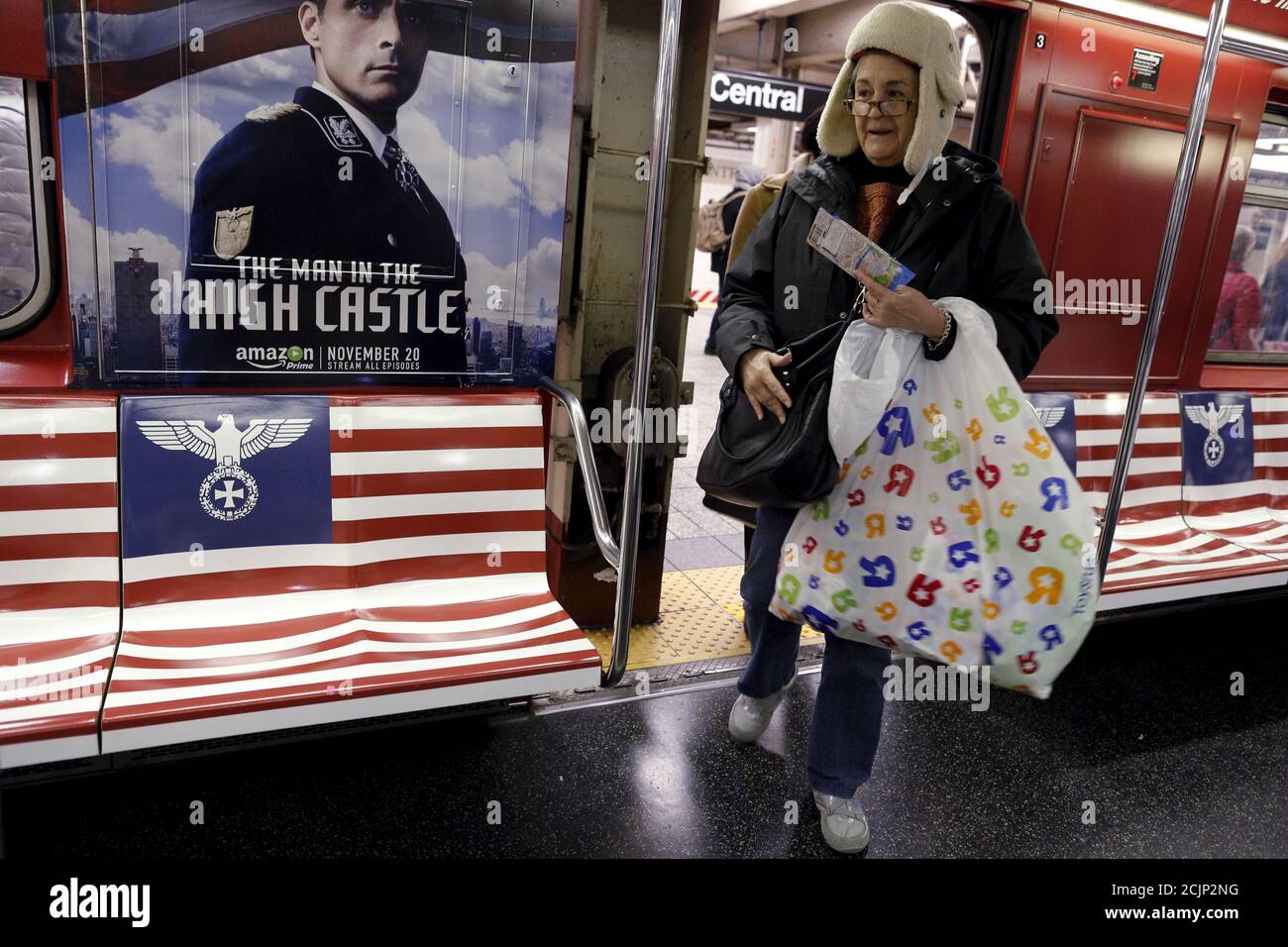 Passagiere steigen in einen U-Bahn-Zug des 42nd Street Shuttle ein, der mit  Werbung für die Amazon-Serie "The man in the High Castle" im Stadtteil  Manhattan von New York, 24. November 2015, verpackt